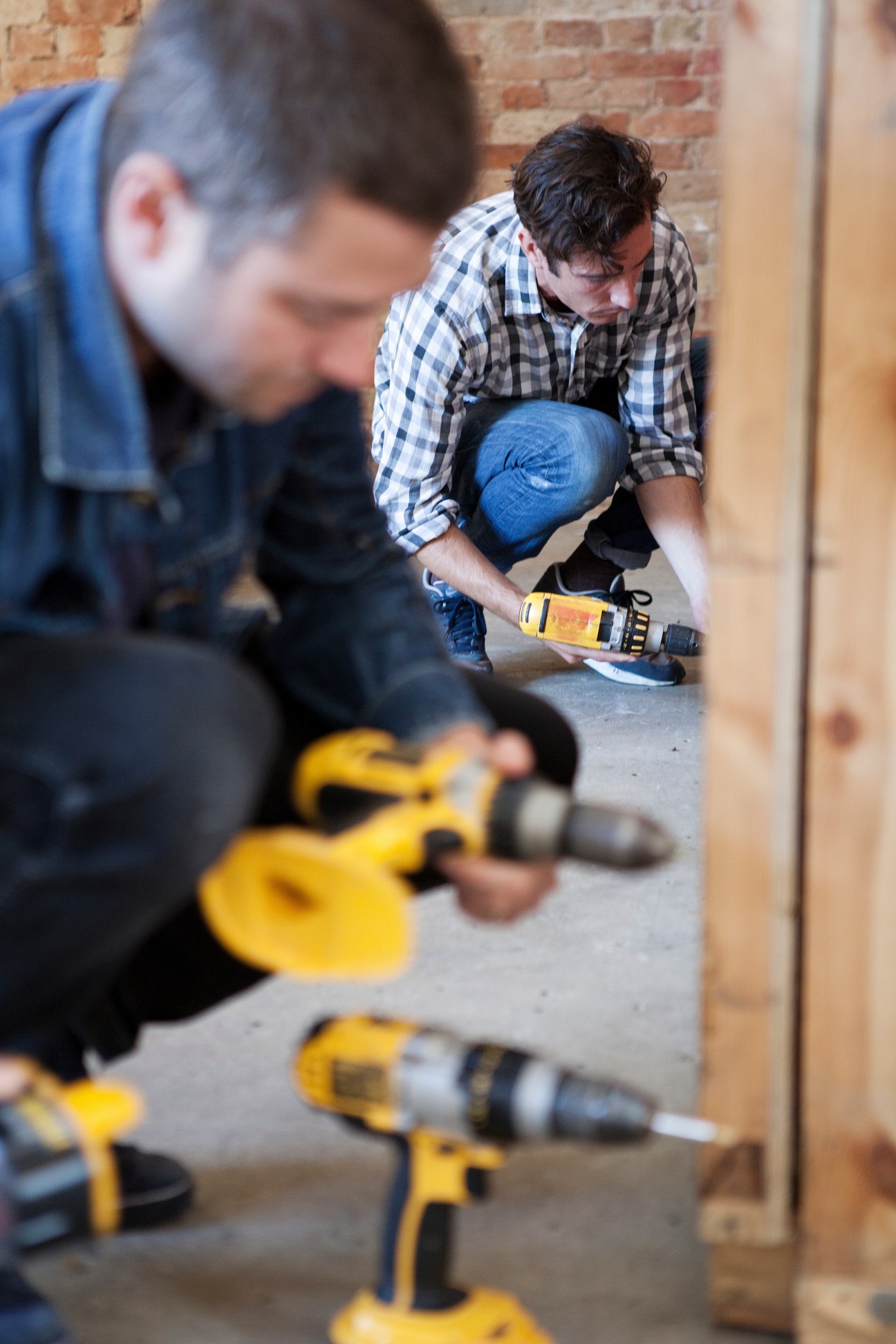 Technicians Tim Summers and Errol Perkins working with power tools on a construction site.