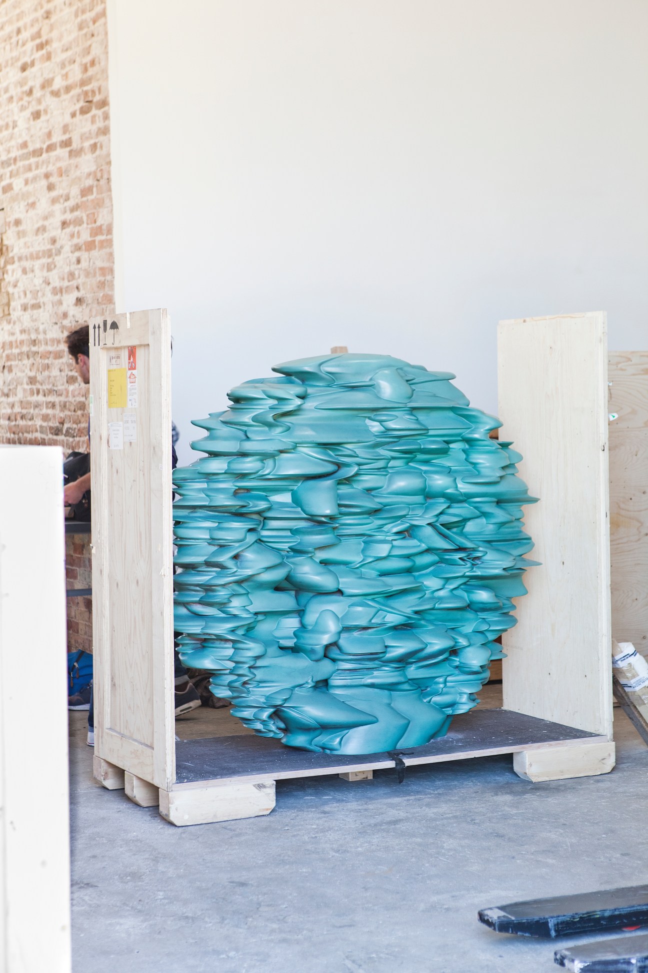 Tony Cragg bronze sculpture 'Versus' (2012) crated for transport, showing turquoise forms stacked inside wooden shipping crate.