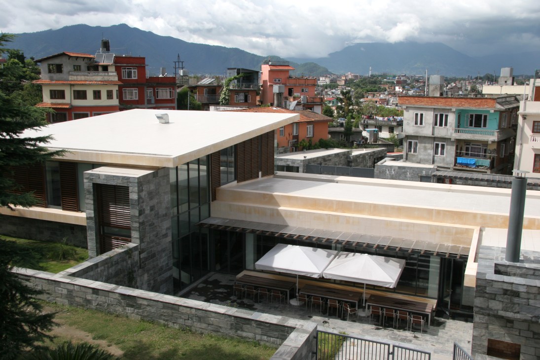 Norwegian Embassy in Kathmandu with slate walls, wooden terraces, and mountain backdrop framed by its zigzag window.