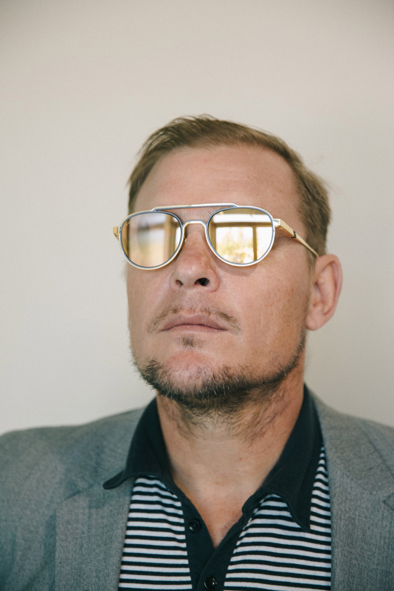 Man wearing Leisure Society sunglasses with gold-plated titanium frames and striped shirt