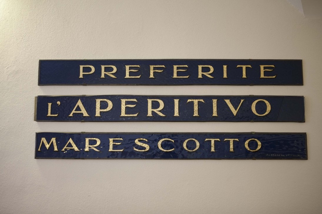 Three navy blue nameplates with gold lettering reading 'PREFERITE', 'L'APERITIVO', and 'MARESCOTTO'