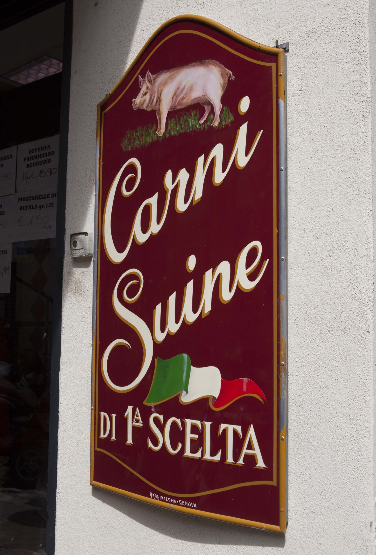 Vintage butcher shop sign with pig illustration and gold-leaf lettering on burgundy background.
