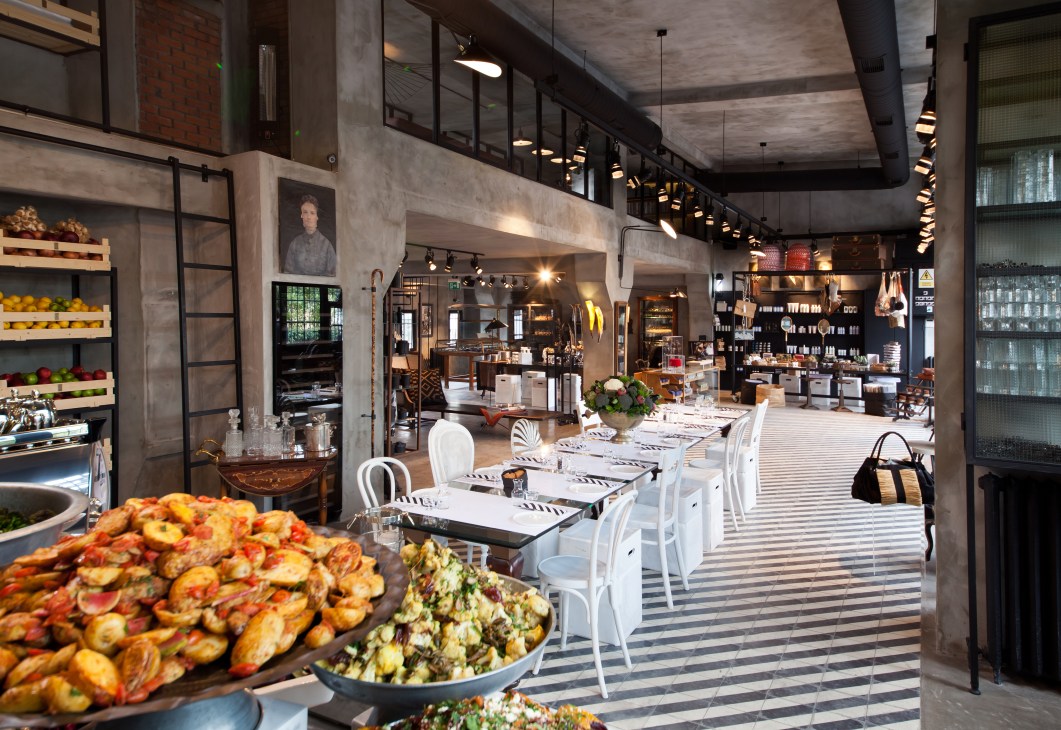 Interior of Sanayi 313 restaurant in Istanbul showing dining tables, fresh produce displays, and design shop shelving.