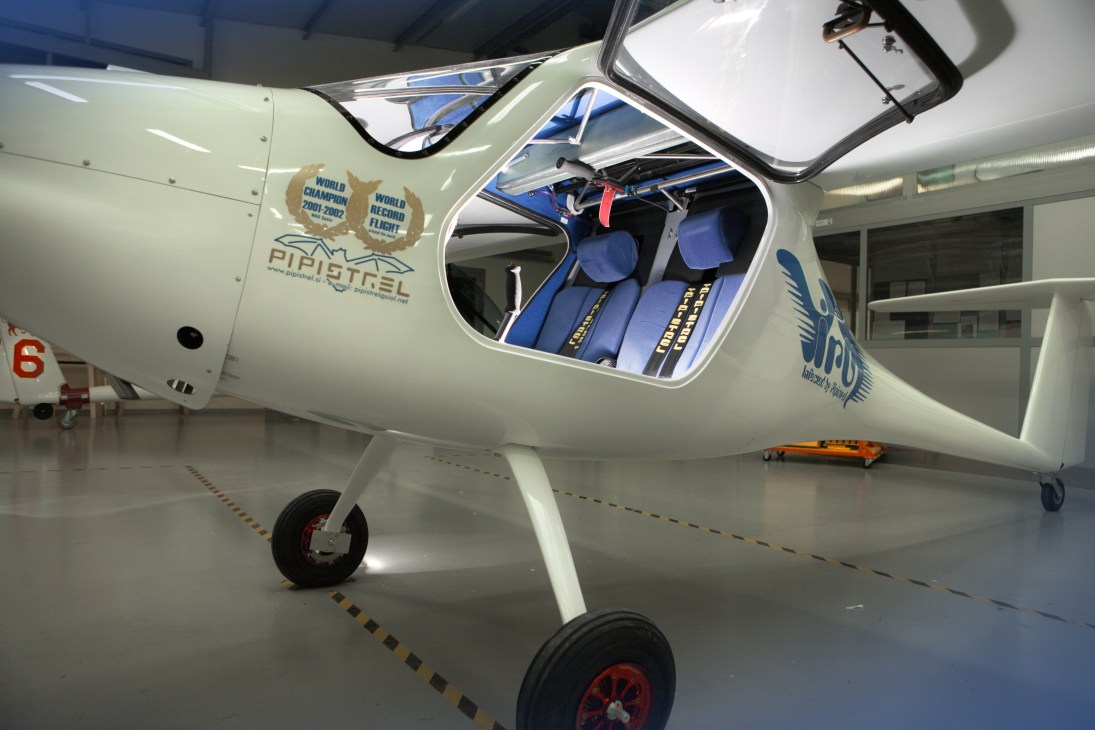 Pipistrel Virus 912 cruise aircraft with open canopy displaying blue interior in hangar.