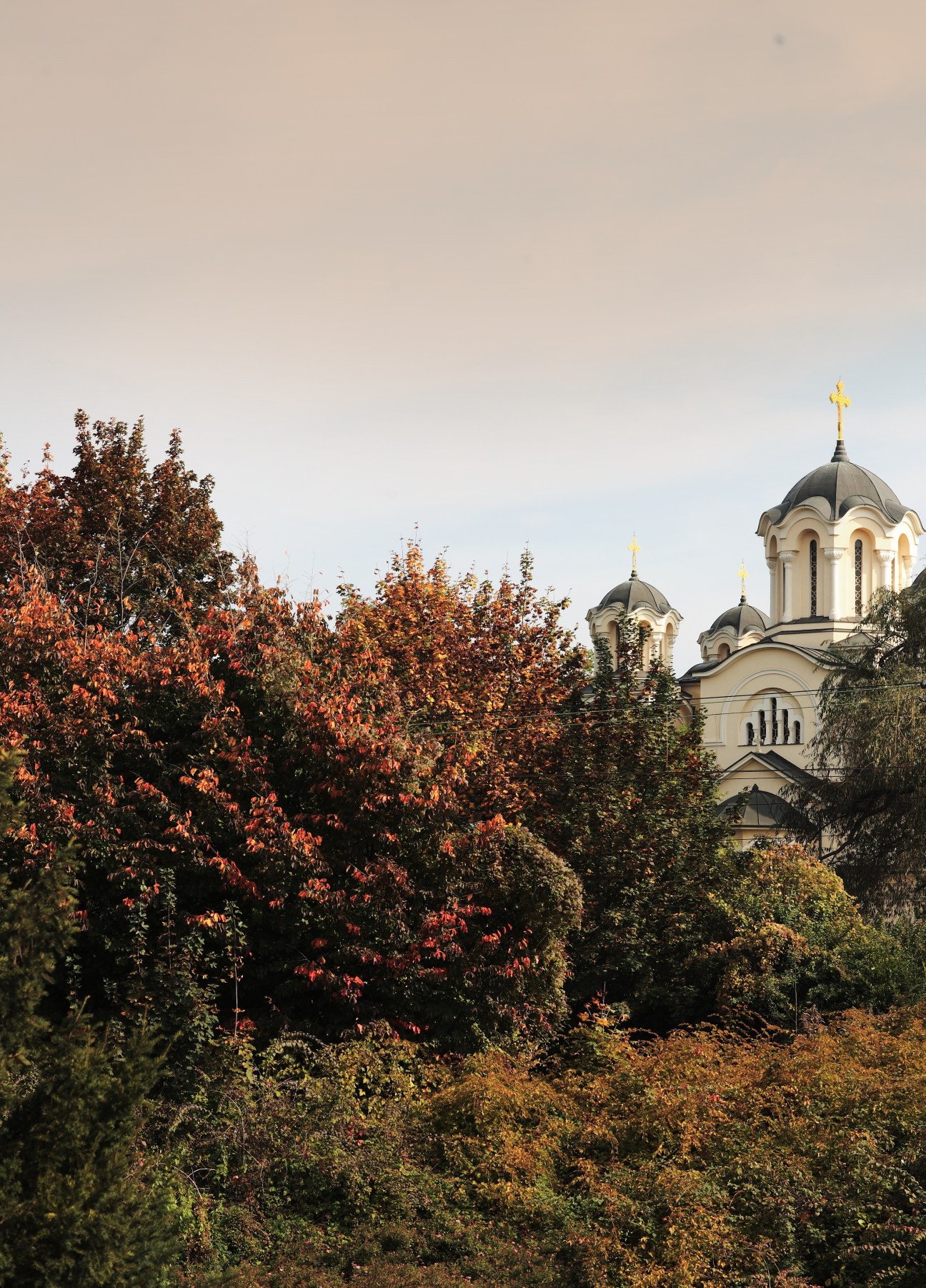 Orthodox church with golden domes surrounded by autumn foliage in Bled, Slovenia.