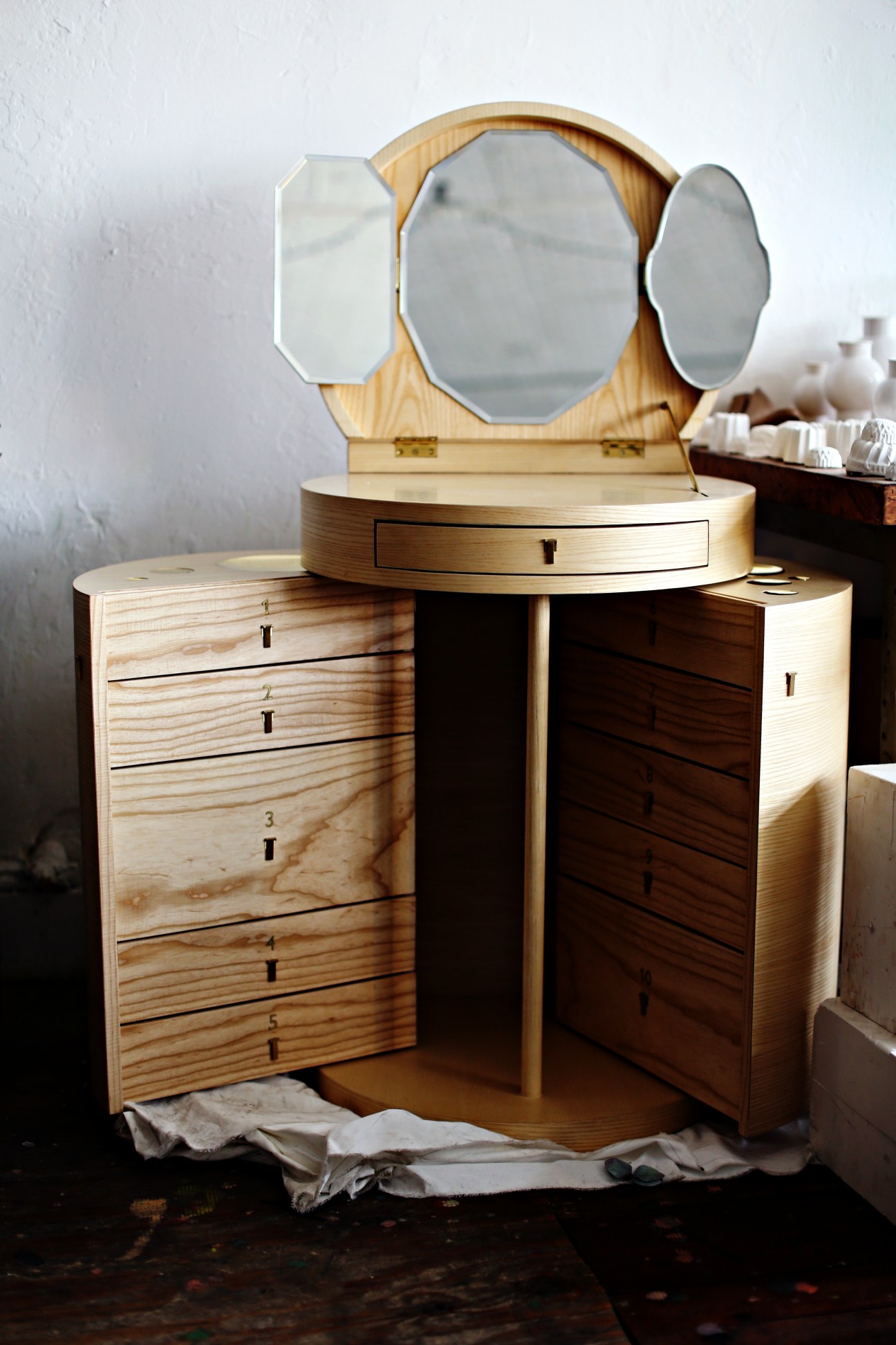 A wooden vanity desk with mirror featuring natural wood finish and drawers.
