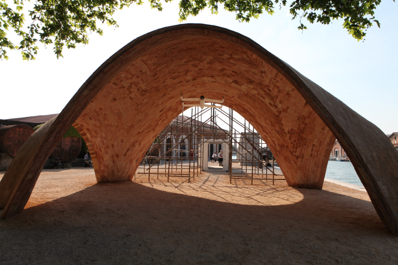 Curved brick archway structure with scaffolding visible through opening at Venice Biennale