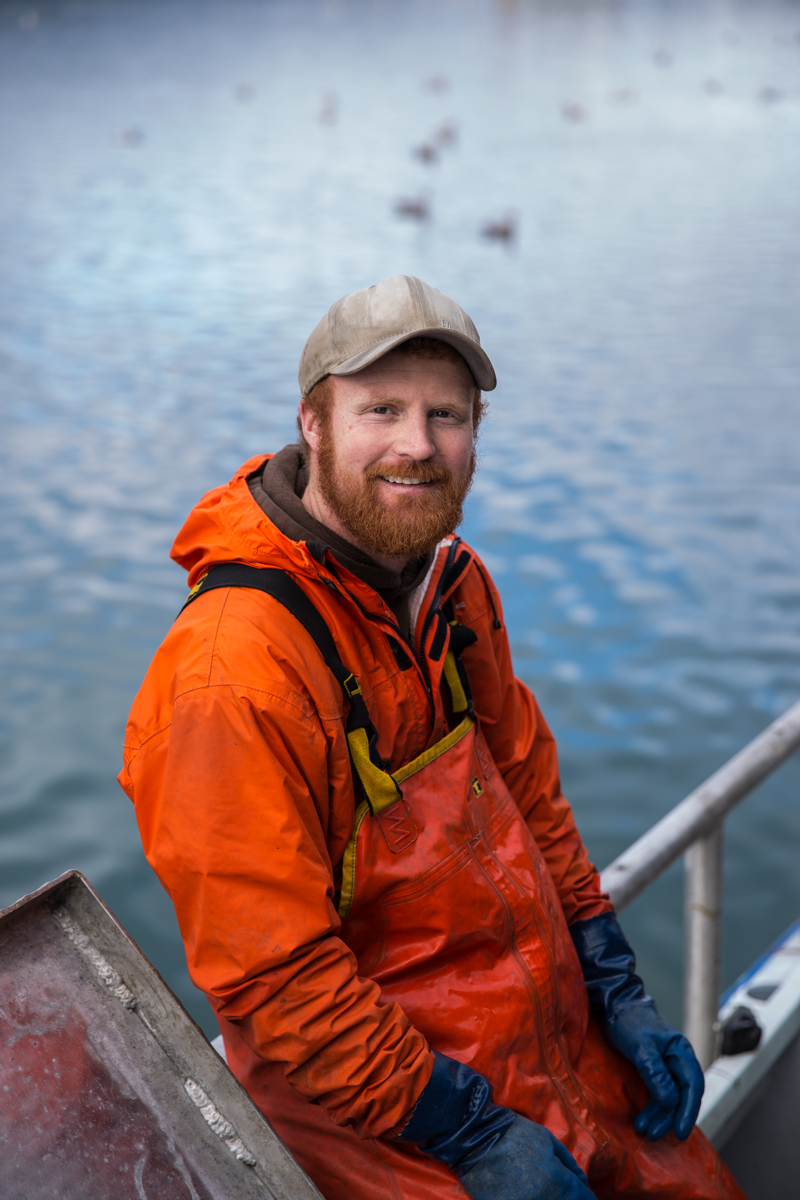 Chad Poppe, skipper of the Lady Leona fishing vessel, wearing an orange jacket and cap on deck.