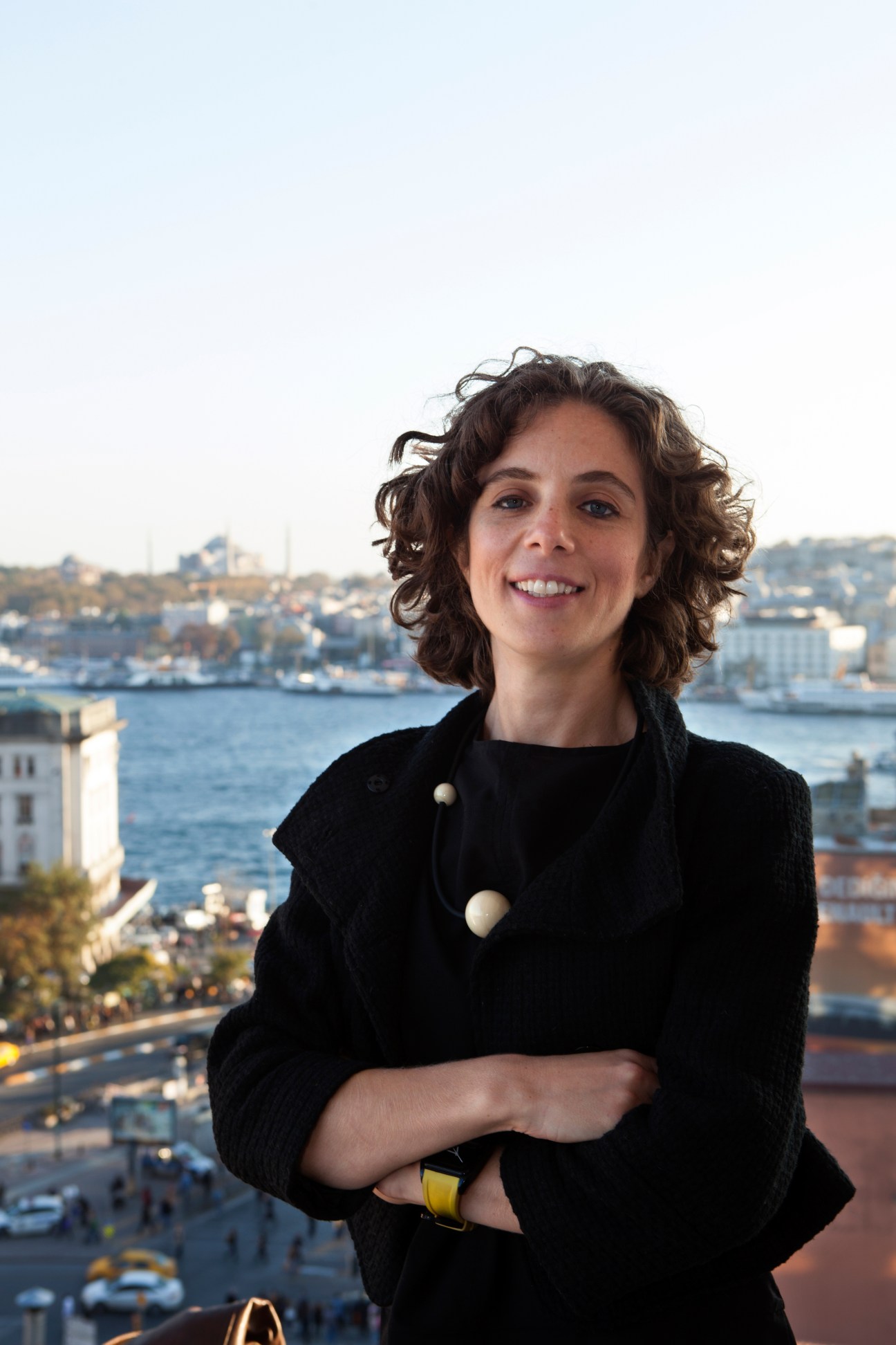 Zeynep Berik, curator of Vault Karakoy hotel, smiles at the camera with Istanbul's Golden Horn in the background.