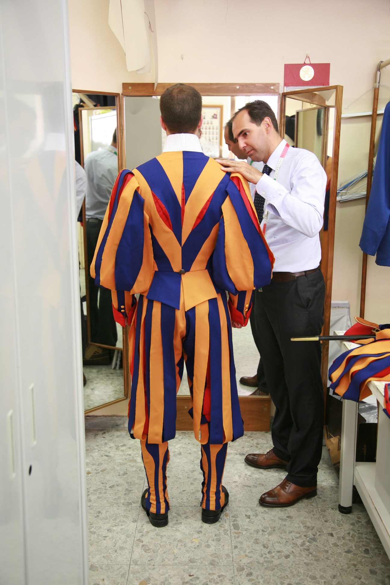 Tailor Ety Cicioni adjusts the shoulder seam of a Swiss Guard's blue, yellow and red striped dress uniform during a fitting.