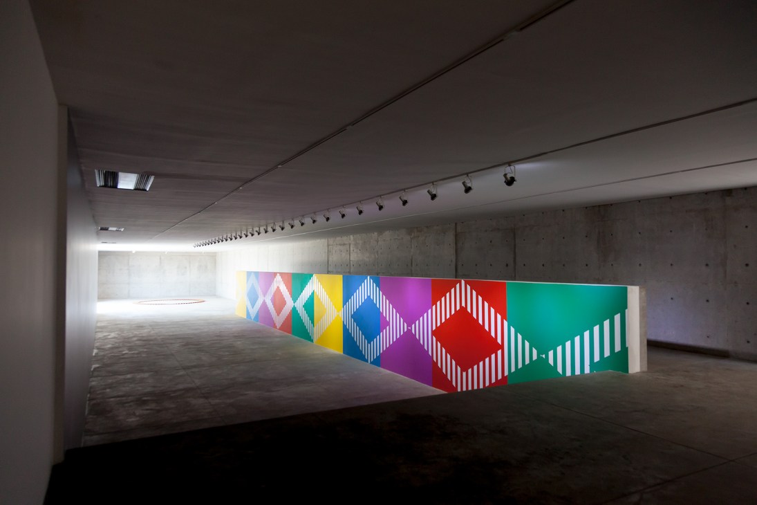 Daniel Buren's colorful geometric artwork displayed in a minimalist concrete gallery space with skylights.
