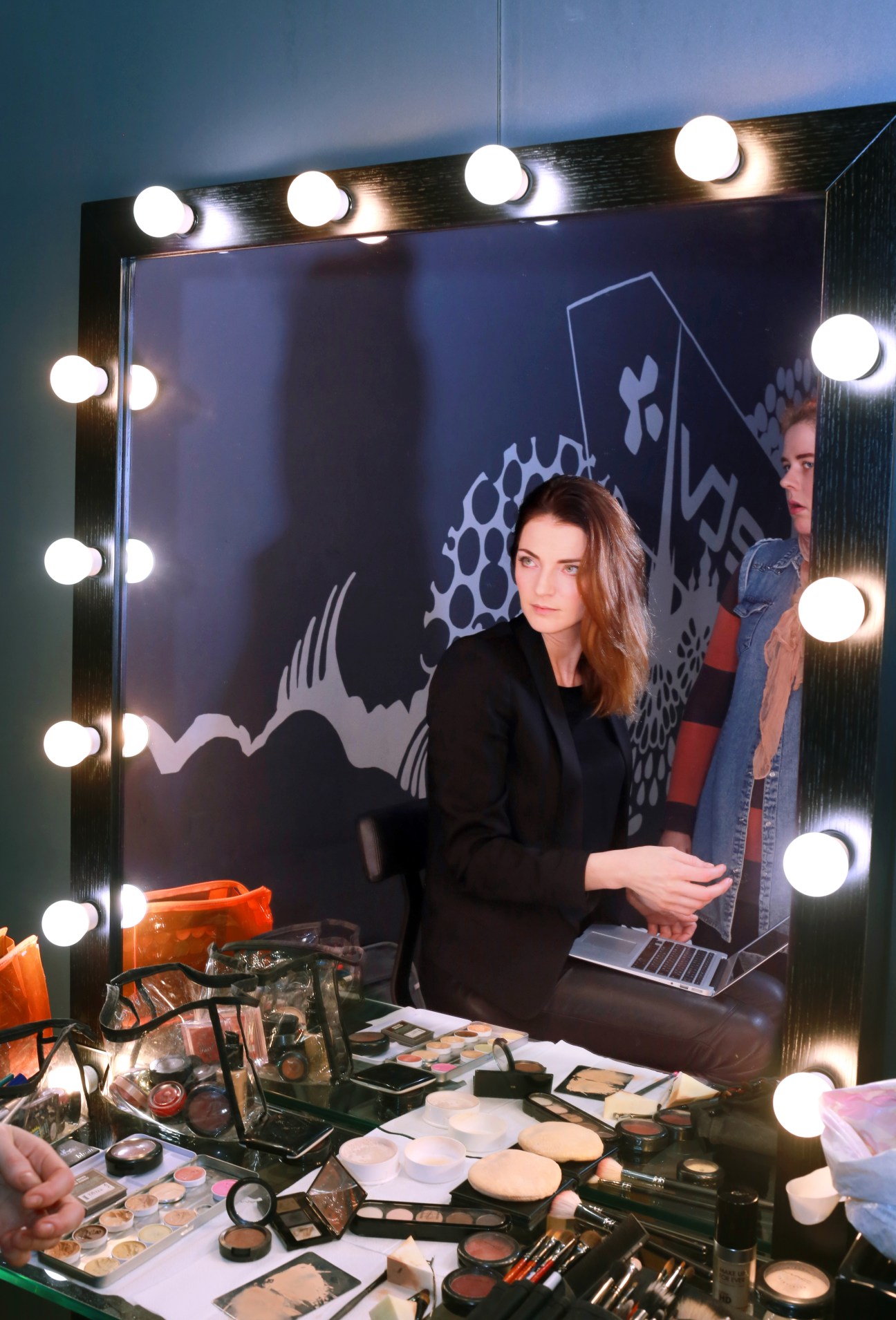 Your Evening presenter Anna Sapronenko in hair and make-up at a mirror with illuminated bulbs.