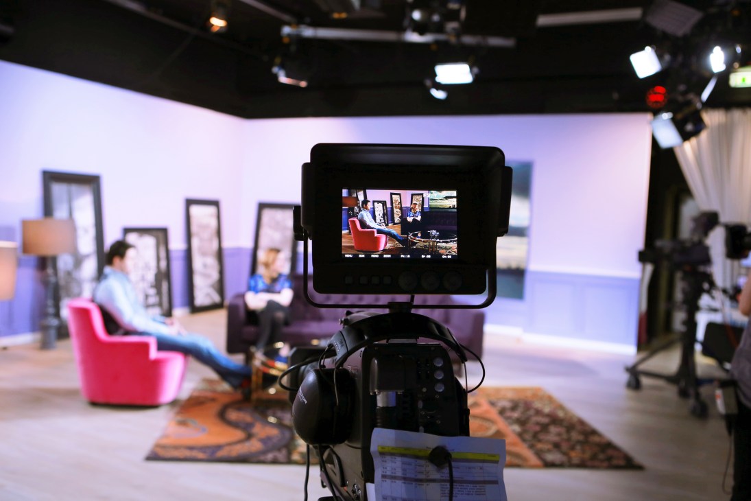 Camera monitor showing a television studio set with red chairs and presenters during filming of 'Your Evening'
