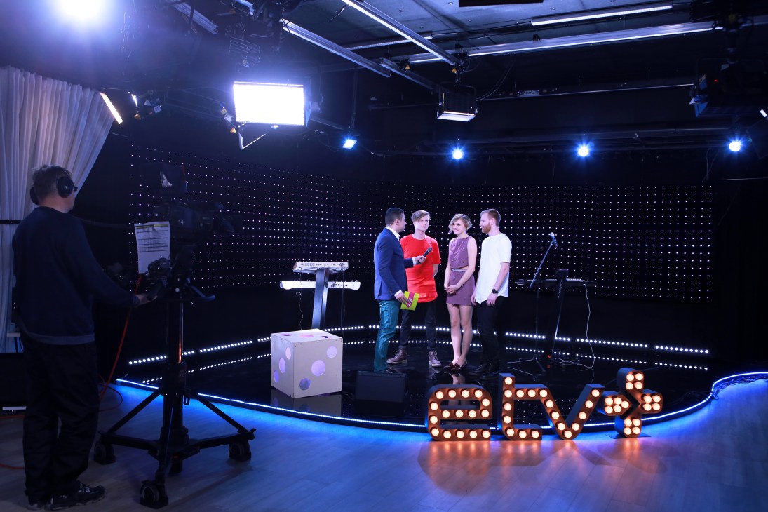 Andrei Titov interviewing members of Estonian band Würffel on the brightly lit studio set of ETV+ television show.