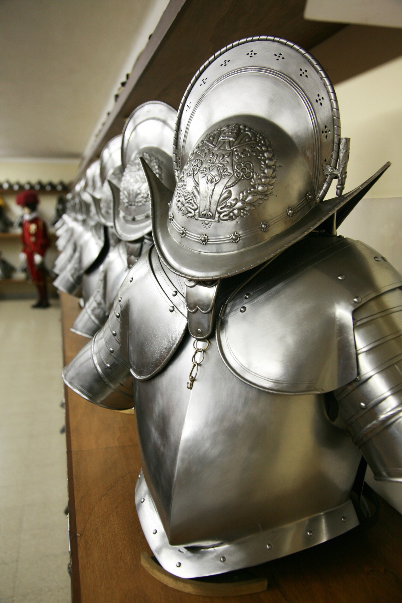 Polished silver ceremonial armor and helmet with ornate details displayed in Vatican barracks.
