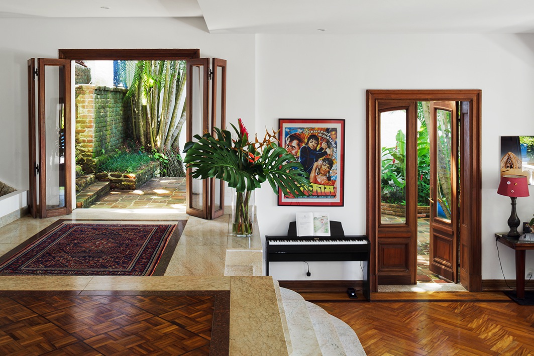 Split-level reception with marble steps, jatoba flooring, wooden doors opening to garden, and period architectural features.