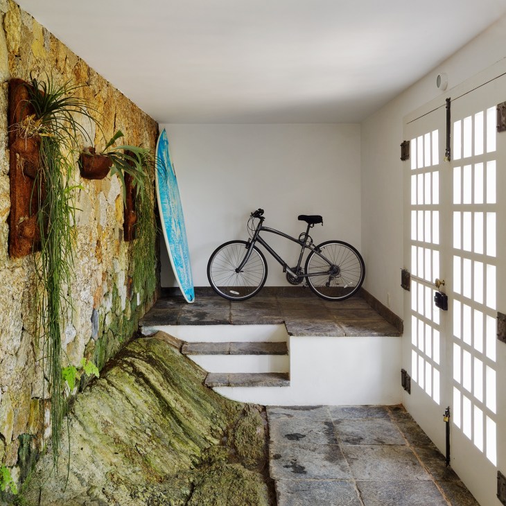Rio residence entrance with rock wall, bicycle, surfboard and white lattice doors