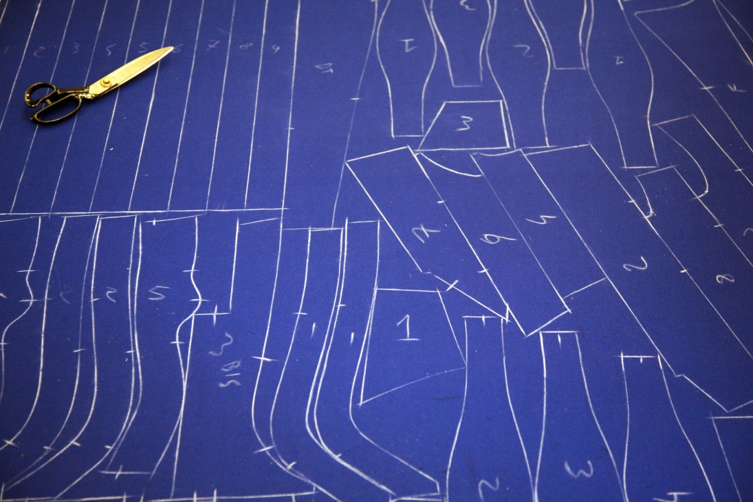 Tailor's scissors and chalk marks on blue Swiss Guard uniform pattern pieces.