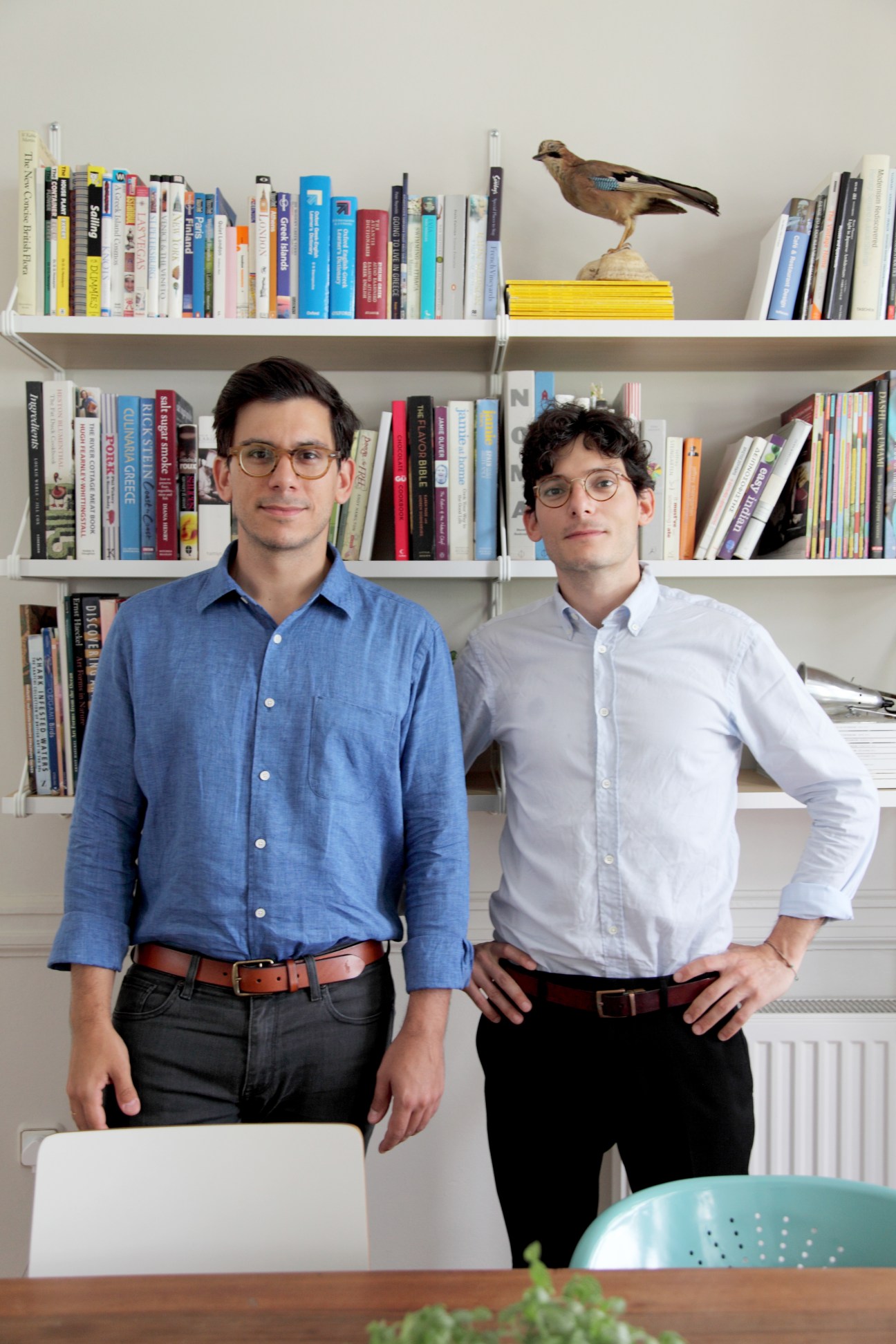 Brothers Dimitris and Konstantinos Karampatakis, founders of K-Studio, standing in front of bookshelves