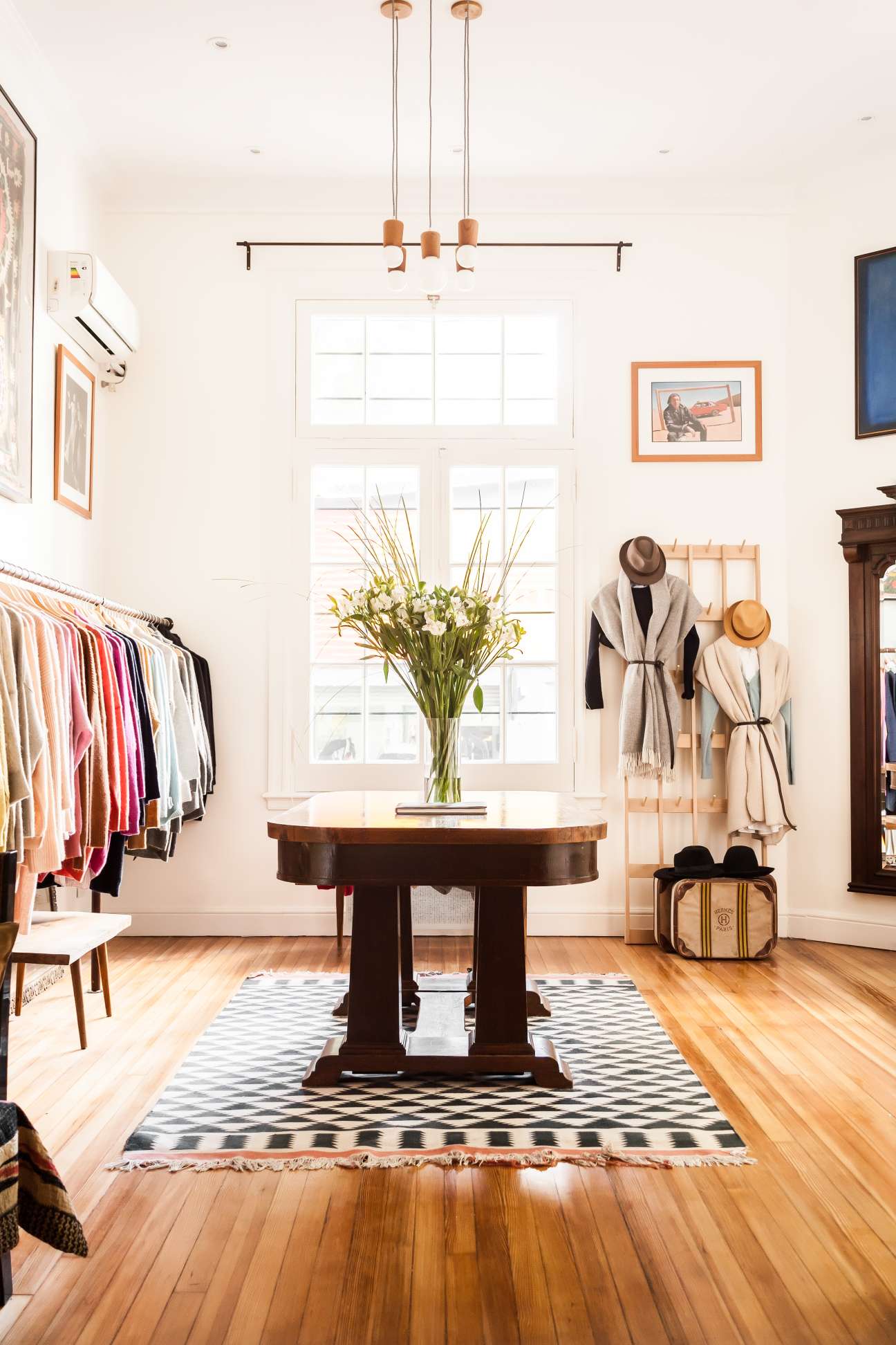 Interior of Blue Sheep boutique with clothing racks, round wooden table, and accessories on display walls.