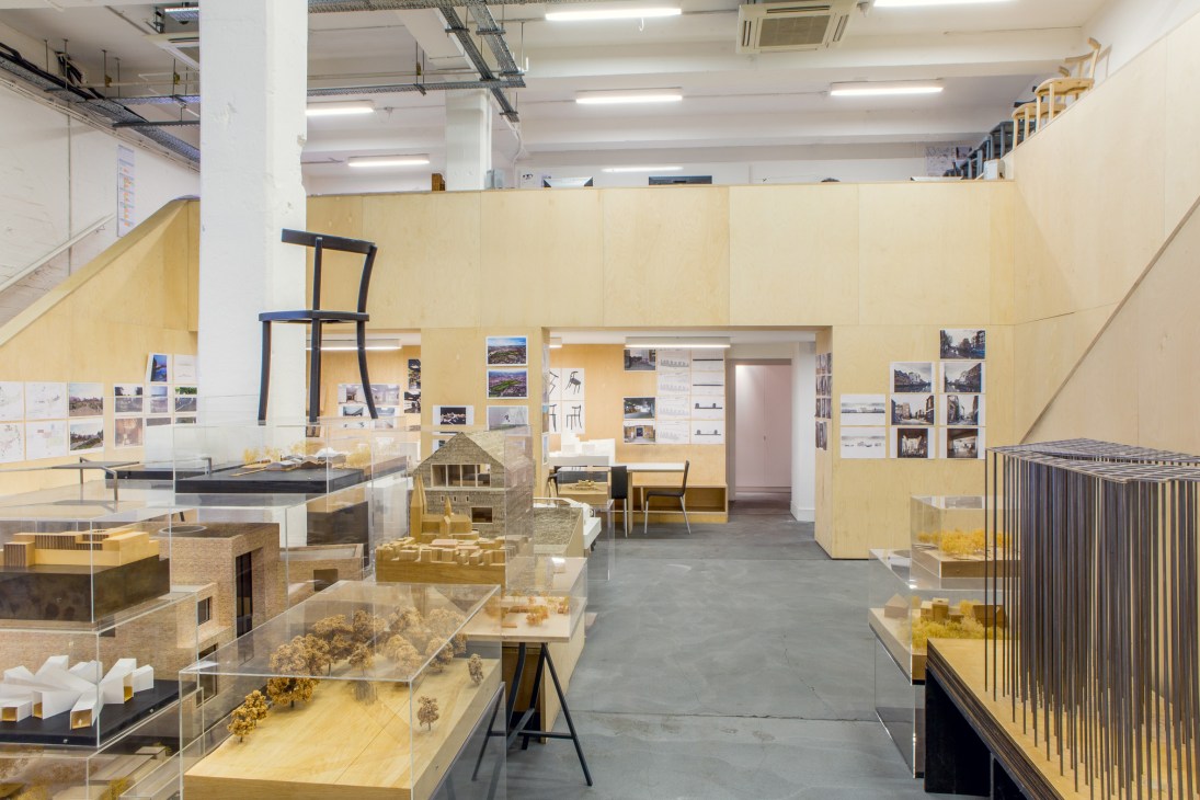 Interior view of architecture studio showing model displays and design workspace with yellow walls.