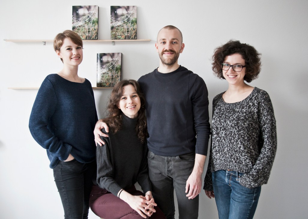 Four members of the Thisispaper team pose together in front of shelves displaying their publications.