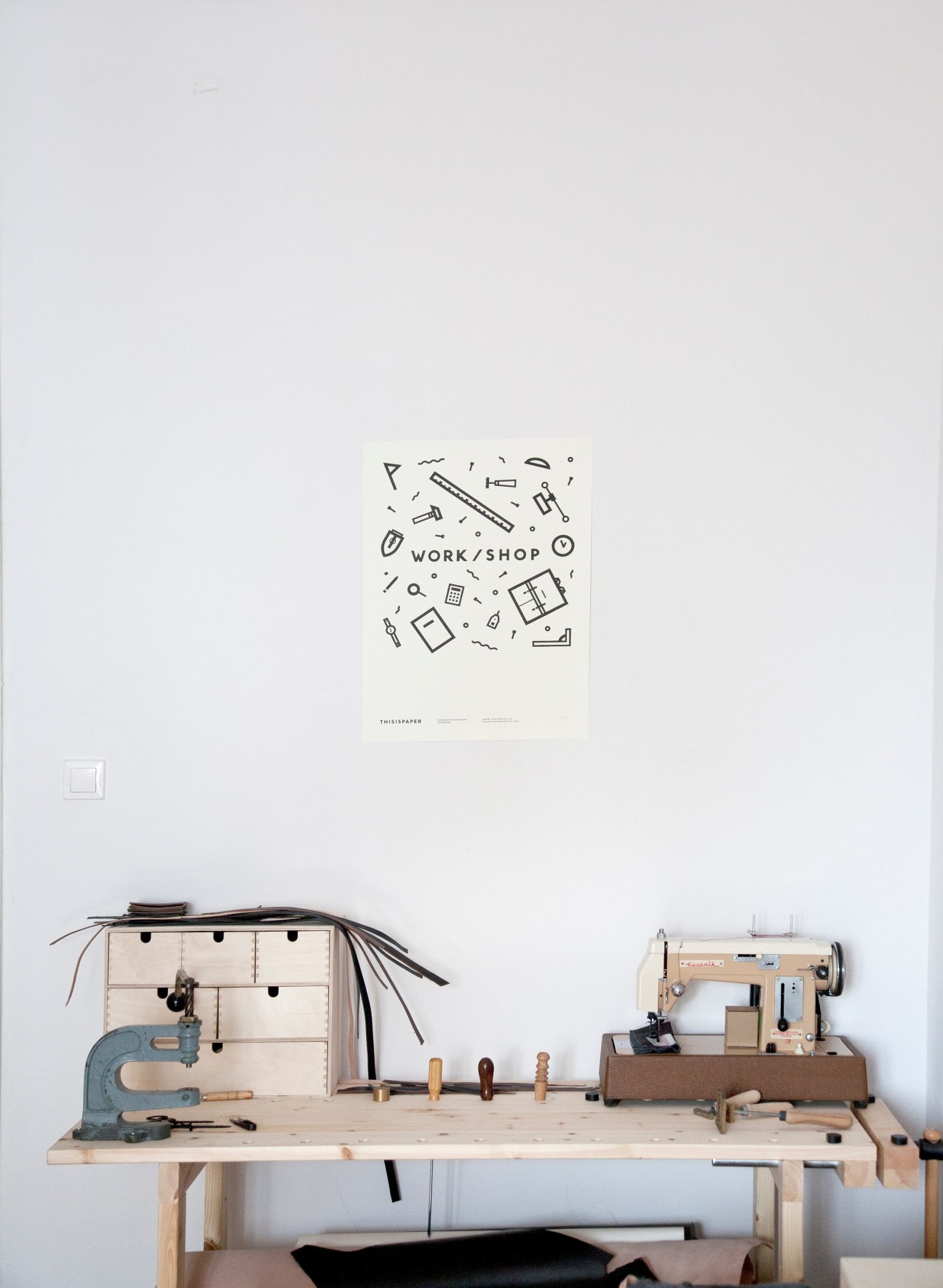Thisispaper workspace with sewing machine, tools and wooden table displaying handmade textiles and accessories.