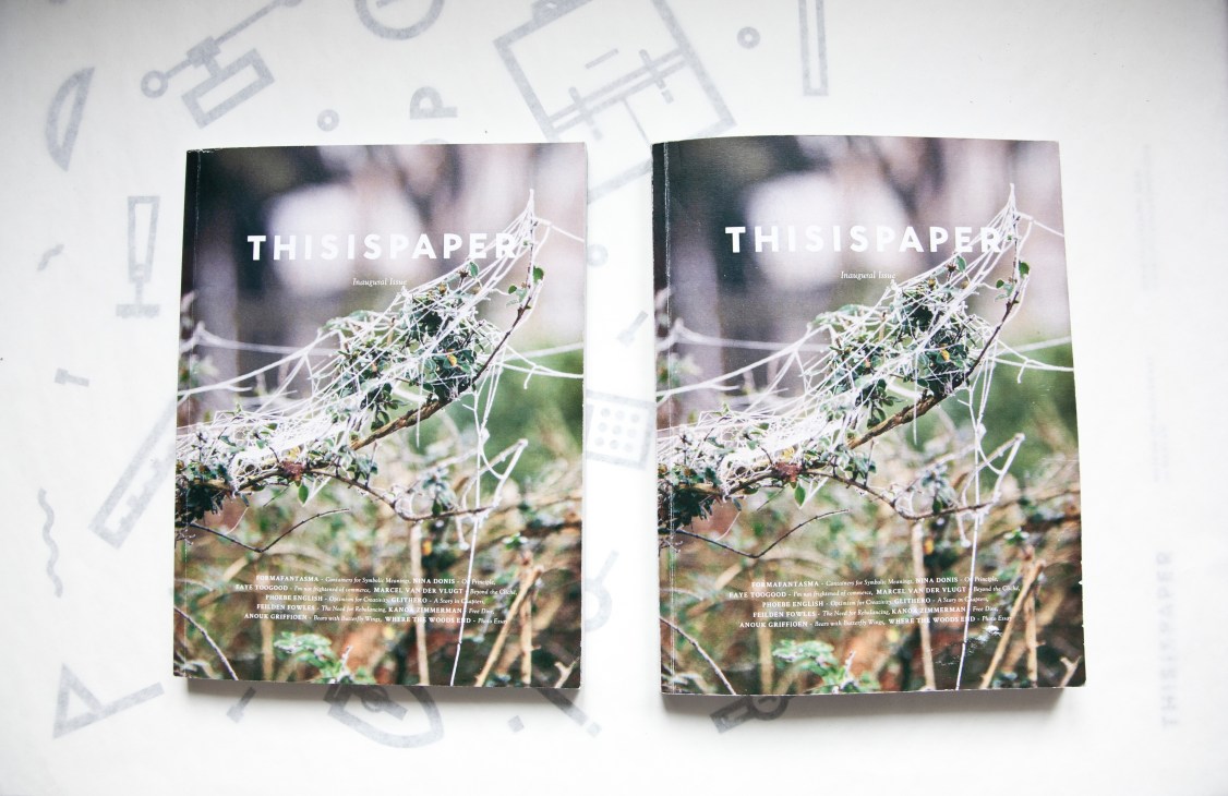 Two copies of Thisispaper magazine's inaugural issue displayed on a white surface with design sketches.