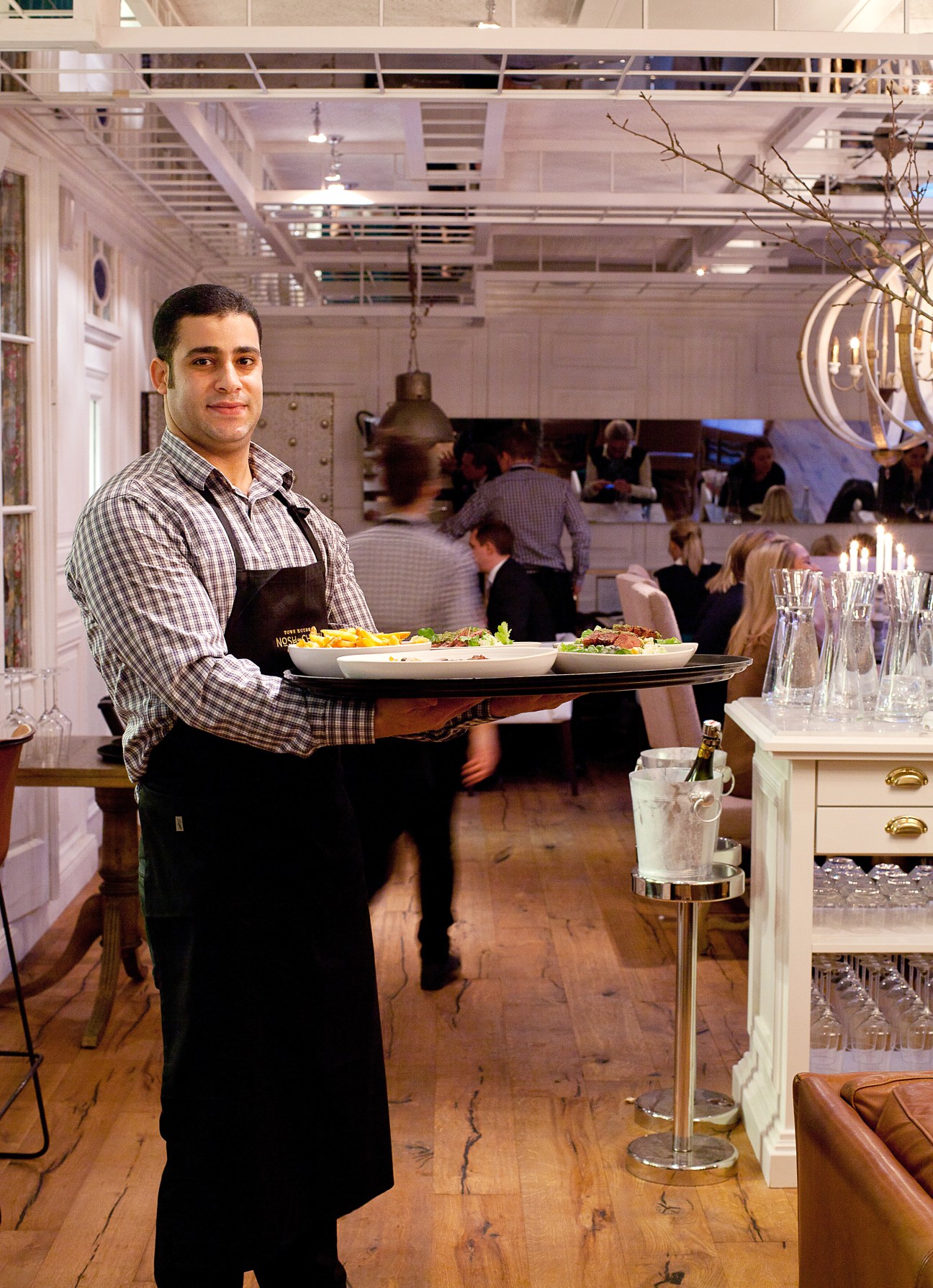 A server holding a tray of food in Nosh and Chow restaurant's dining room.