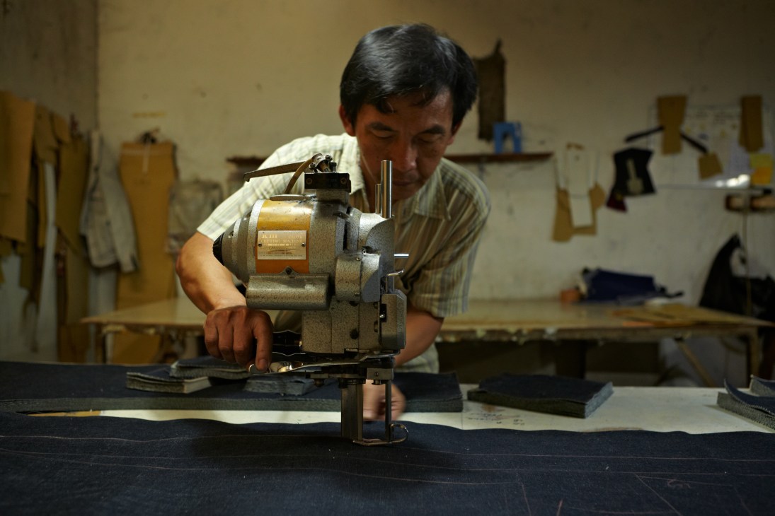 Craftsman operating an industrial cutting machine in Pot Meets Pop's denim factory in Bandung.