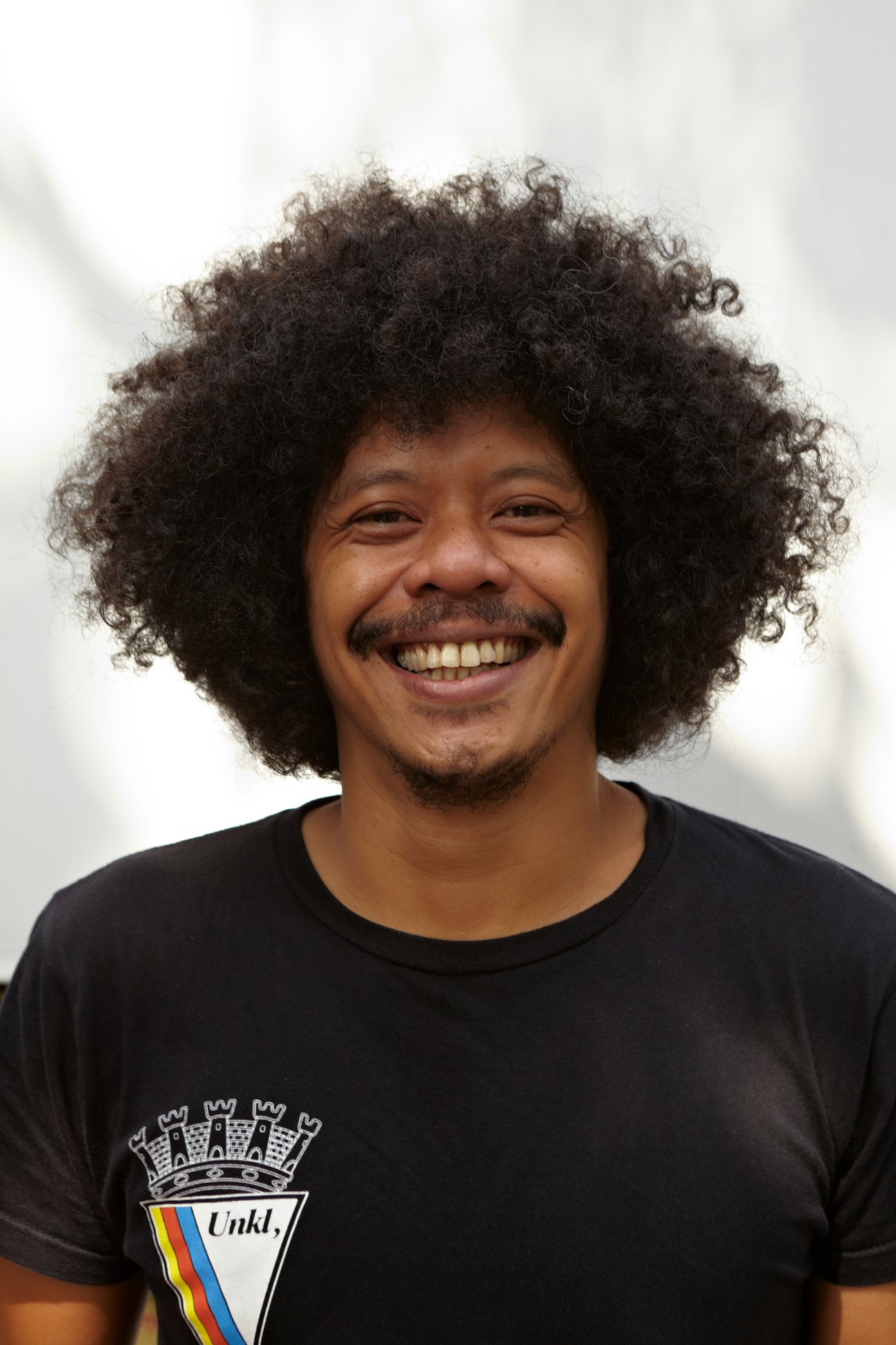 Edi Brokoli of UNKL347 smiling at the camera wearing a black UNKL347 branded t-shirt.