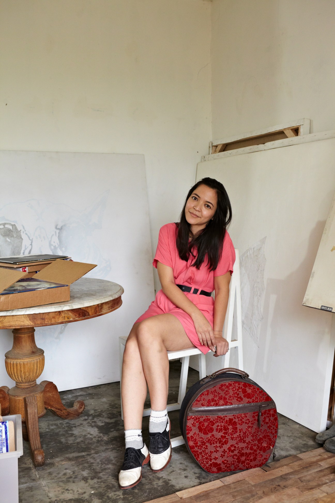 Artist Syagini Ratna Wulan sitting in her studio wearing a pink shirt