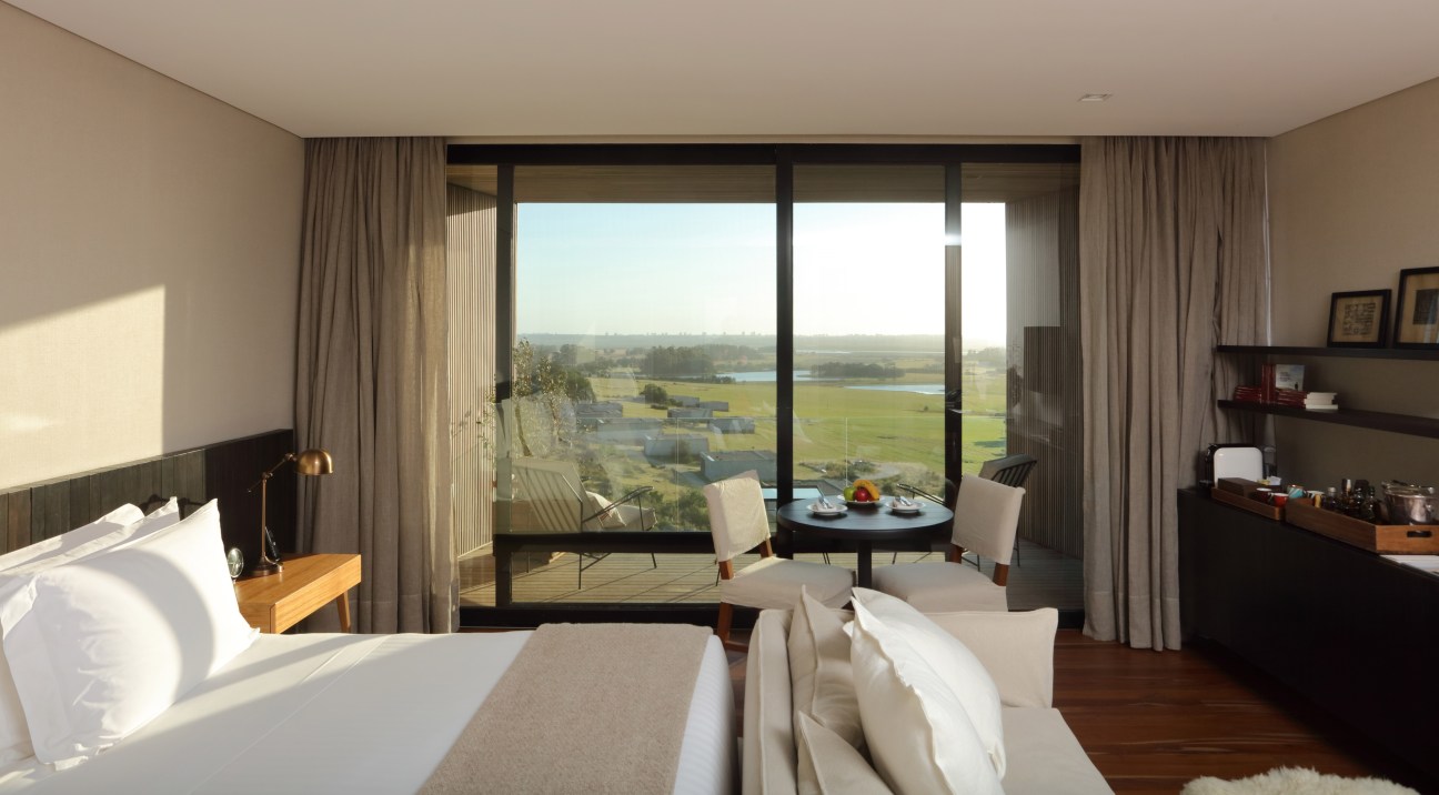 Modern hotel bedroom with large windows overlooking pastoral landscape at La Locanda Fasano.