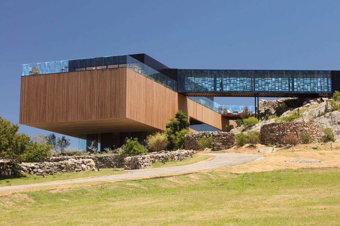 Modern hotel building with wooden and metal cladding perched on rocky outcrop in Punta del Este.