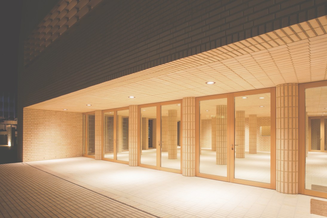 Modern foyer with brick columns, wooden partitions and warm lighting in Liechtenstein's parliament building.