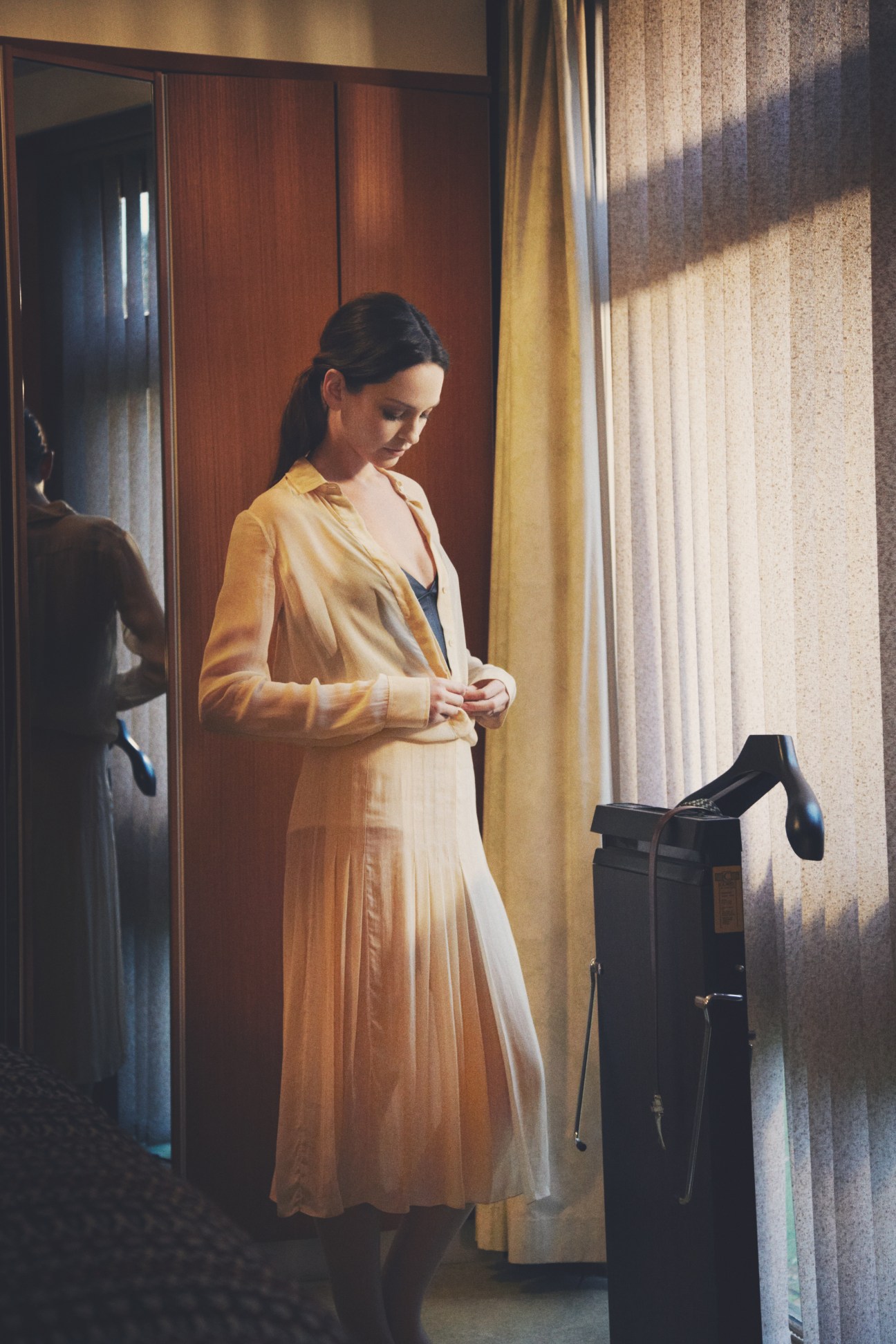 Woman wearing a Céline shirt, bra and skirt with Falke tights in a modernist interior space.