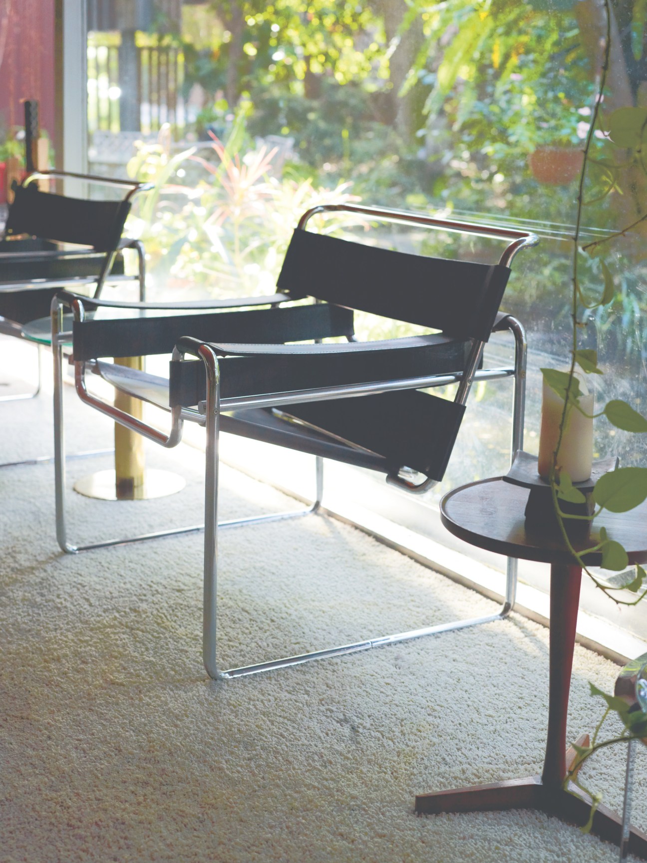 Wassily chairs designed by Marcel Breuer with black canvas sling seating and tubular metal frames on a patio overlooking a garden.