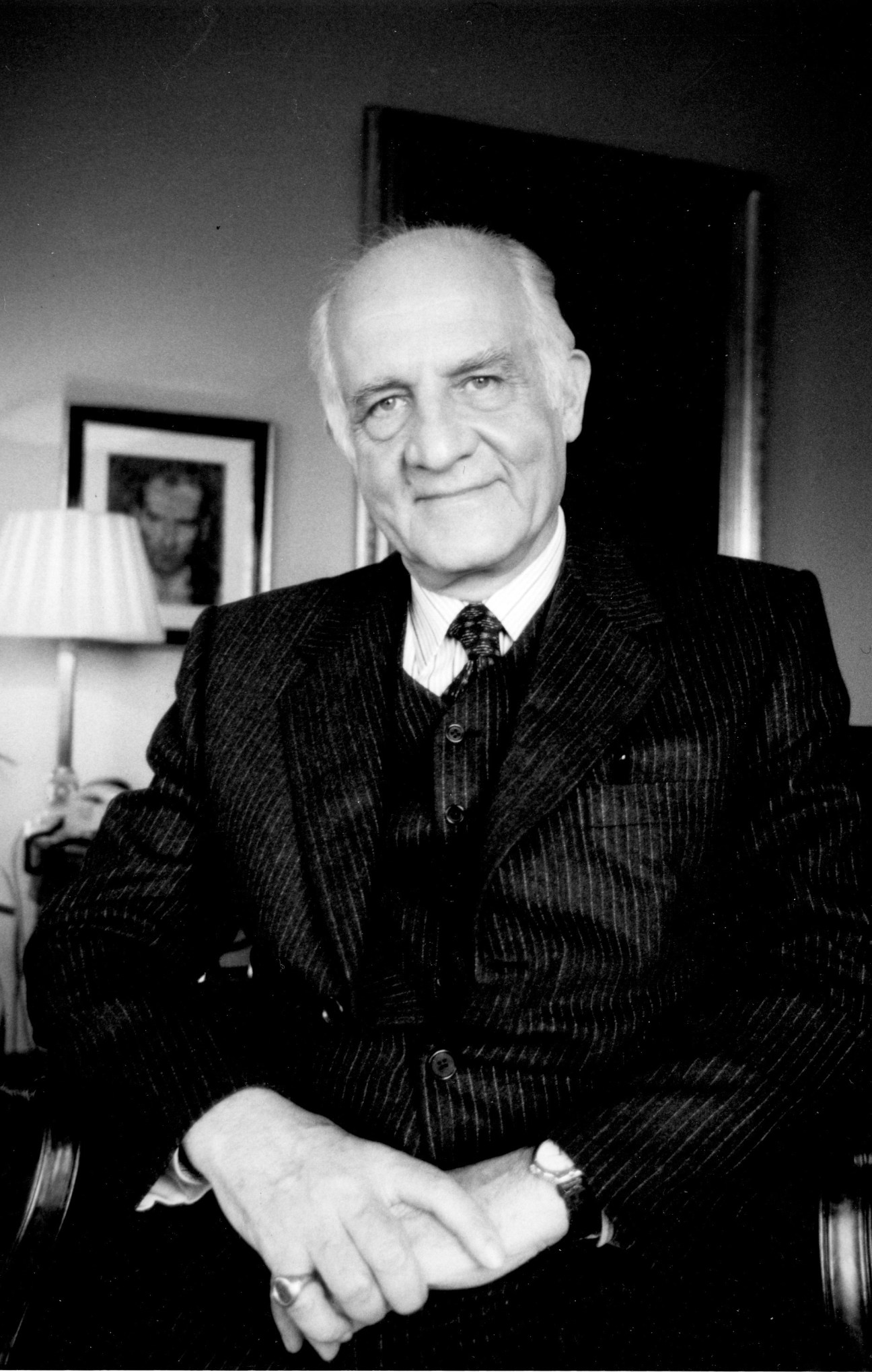 Black and white portrait of Inan Kirac, Turkish art collector, in a pinstriped suit and tie.