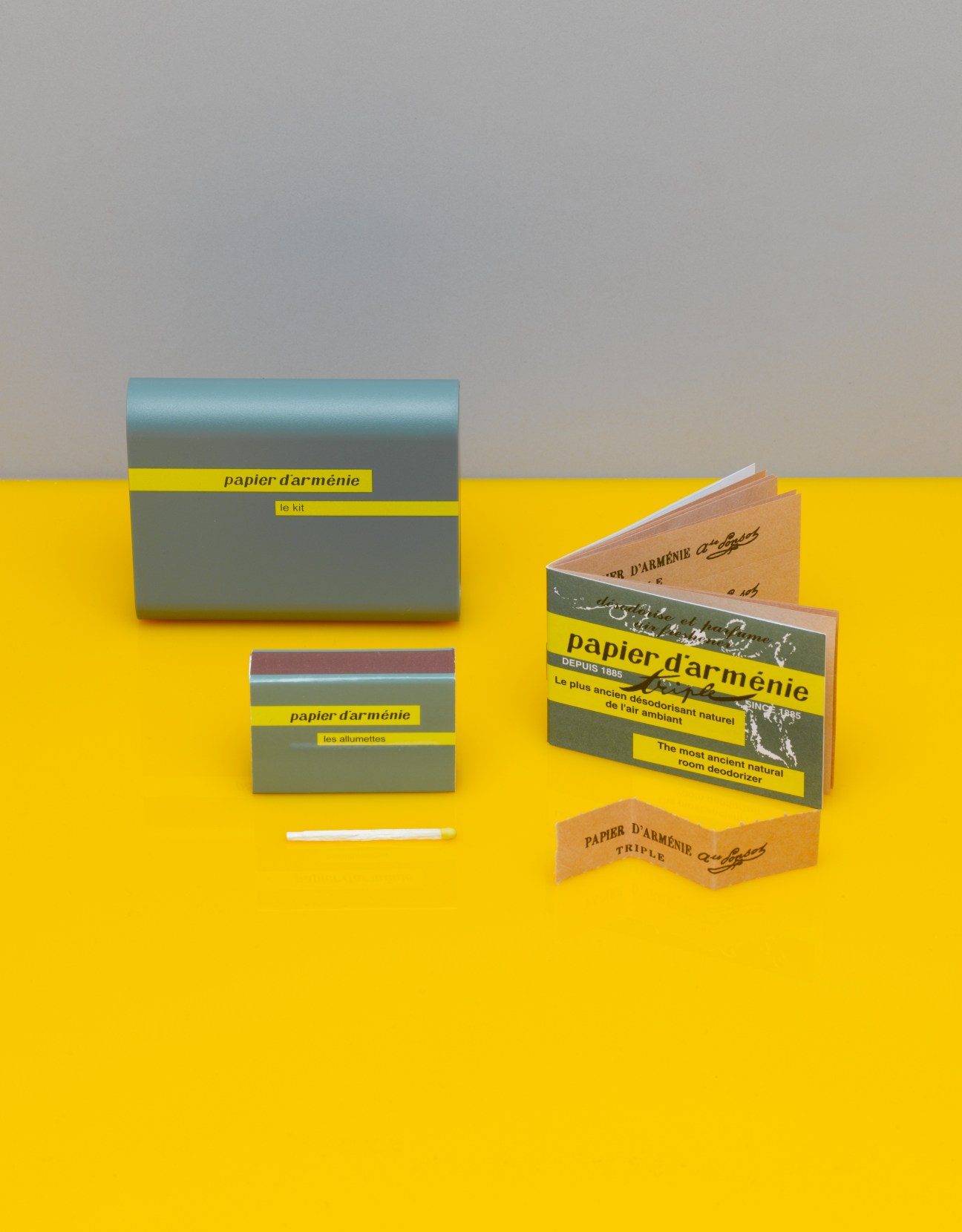 Papier d'Arménie incense products including boxes, strips and matches arranged on yellow background.