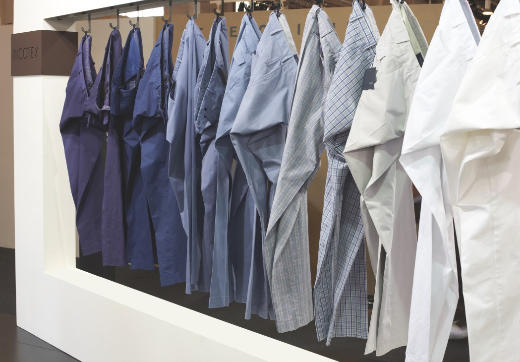 Precision-cut trousers by Incotex hung on a rail, showing navy, light blue, checkered and white styles.