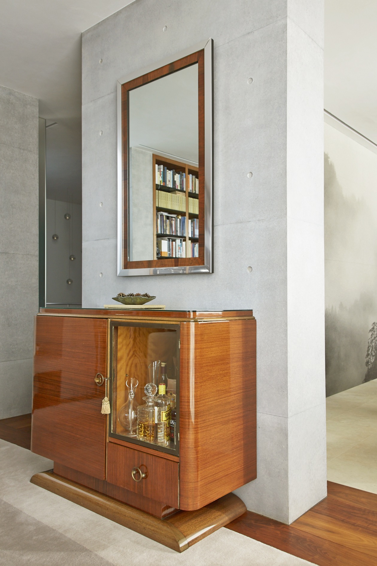 Modern bathroom vanity with wood-framed mirror and shelving displaying books and toiletries.