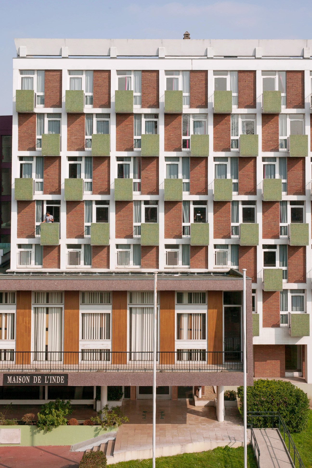 Maison de l'Inde building with red brick facade, white frames, and green balconies at Cité Universitaire Paris.