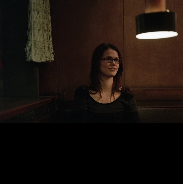 Woman wearing glasses in dark interior with pendant lamp overhead