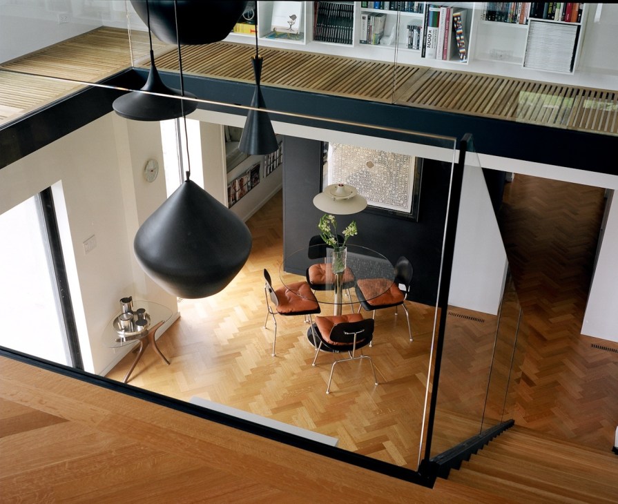 Modern mezzanine interior with black pendant lamp, dining table, and built-in shelving in a Habitat 67 unit.