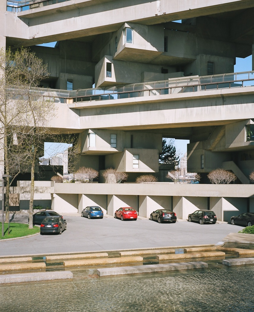 Habitat 67's stacked concrete cube units with car park and St Lawrence River waterfront below.