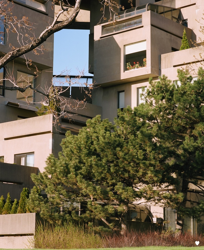 Stacked concrete cube units of Habitat 67 with cut-out windows framing sky views between blocks.