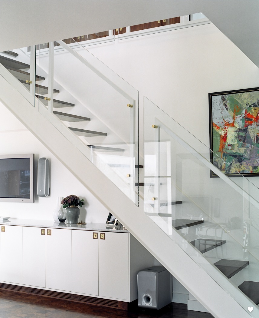 Modern white staircase with glass railing and grey steps in a Habitat 67 unit.