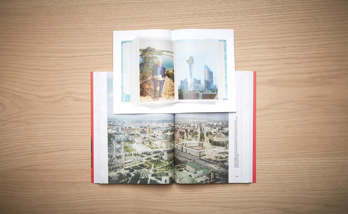 Open book with aerial city photographs displayed on wooden surface.