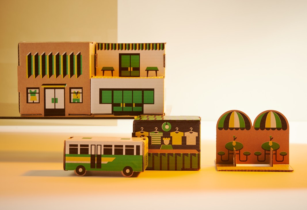 Papierowe Miasto cardboard paper town sets with folded buildings, bus, market stall and park pieces in green, yellow and brown.