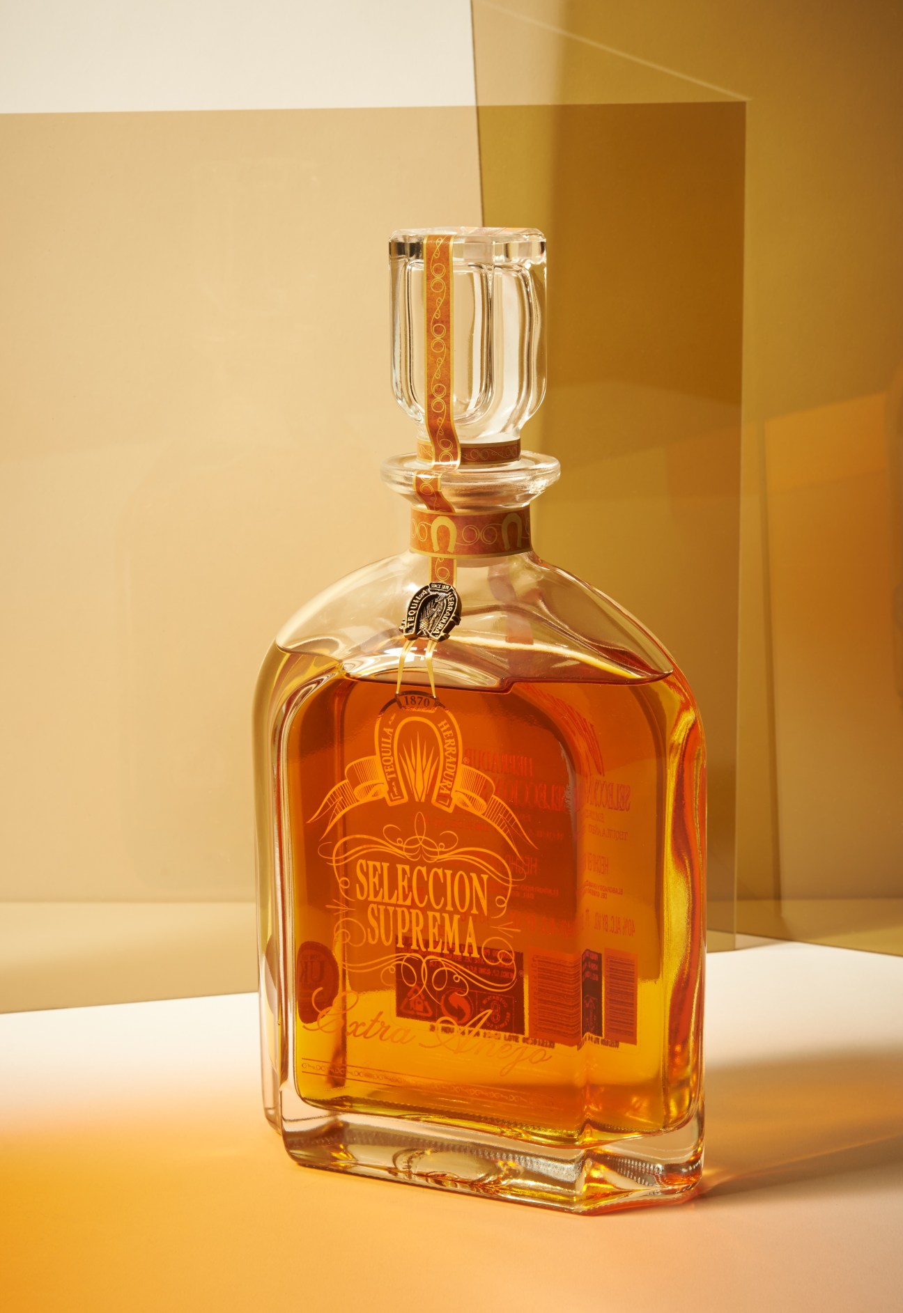 Herradura Selección Suprema extra añejo tequila bottle with amber liquid and leather neck strap.